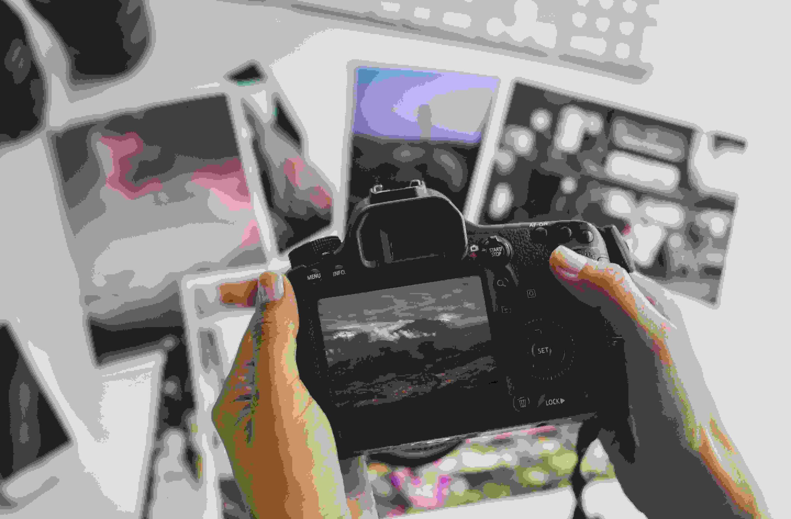 hands holding camera with photographs table photographer working his office 1 scaled